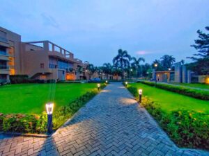 Best weekend resorts near Kolkata with a peaceful garden, palm trees, and a well-lit walking path.